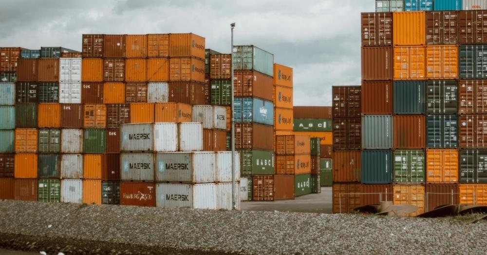 Tall stacks of multicolored shipping containers at a port.