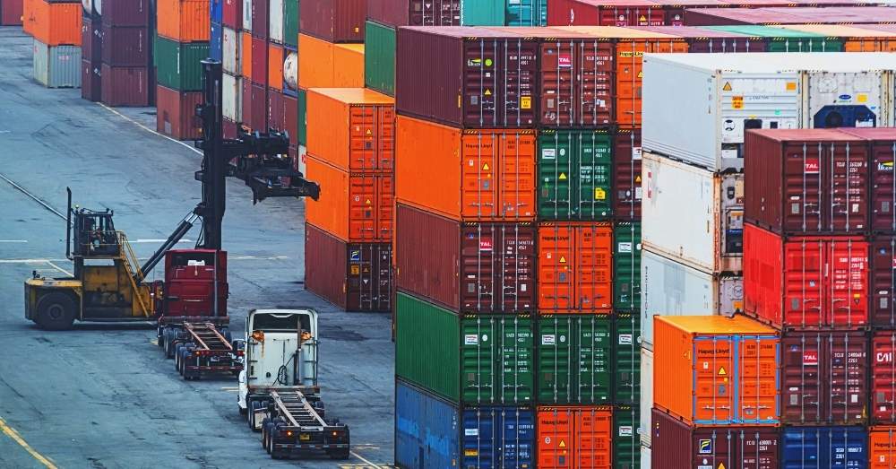 Container stacks and trucks at port for drayage services.