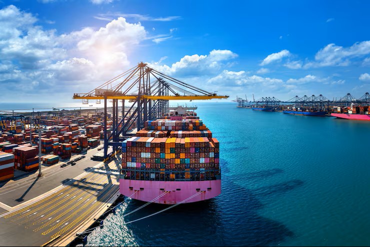 A large container ship docked at a busy port with stacked shipping containers and gantry cranes loading and unloading cargo at sunrise — drayage in logistics.