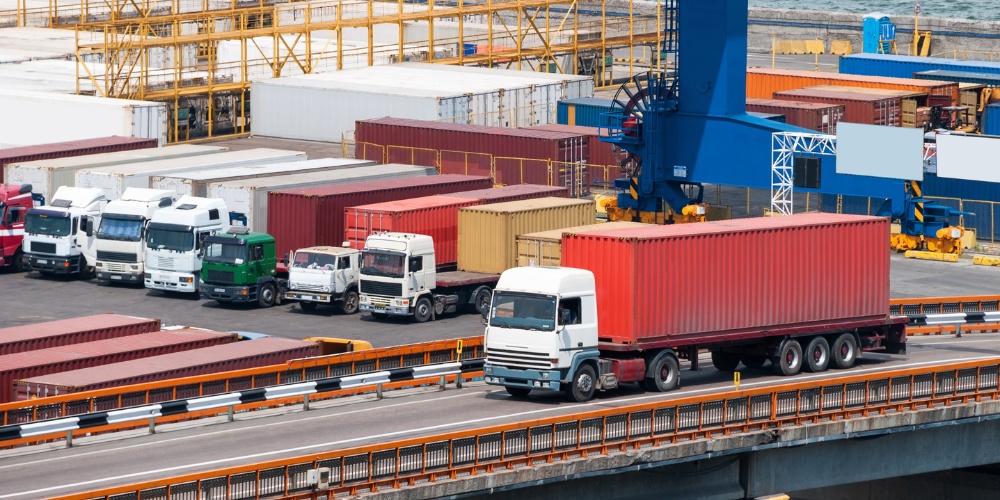 white semi-truck hauling a red shipping container