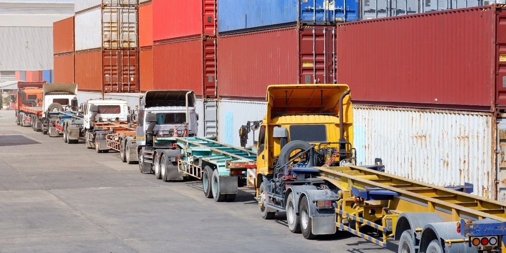 long row of semi-trucks with empty flatbed skeleton trailers